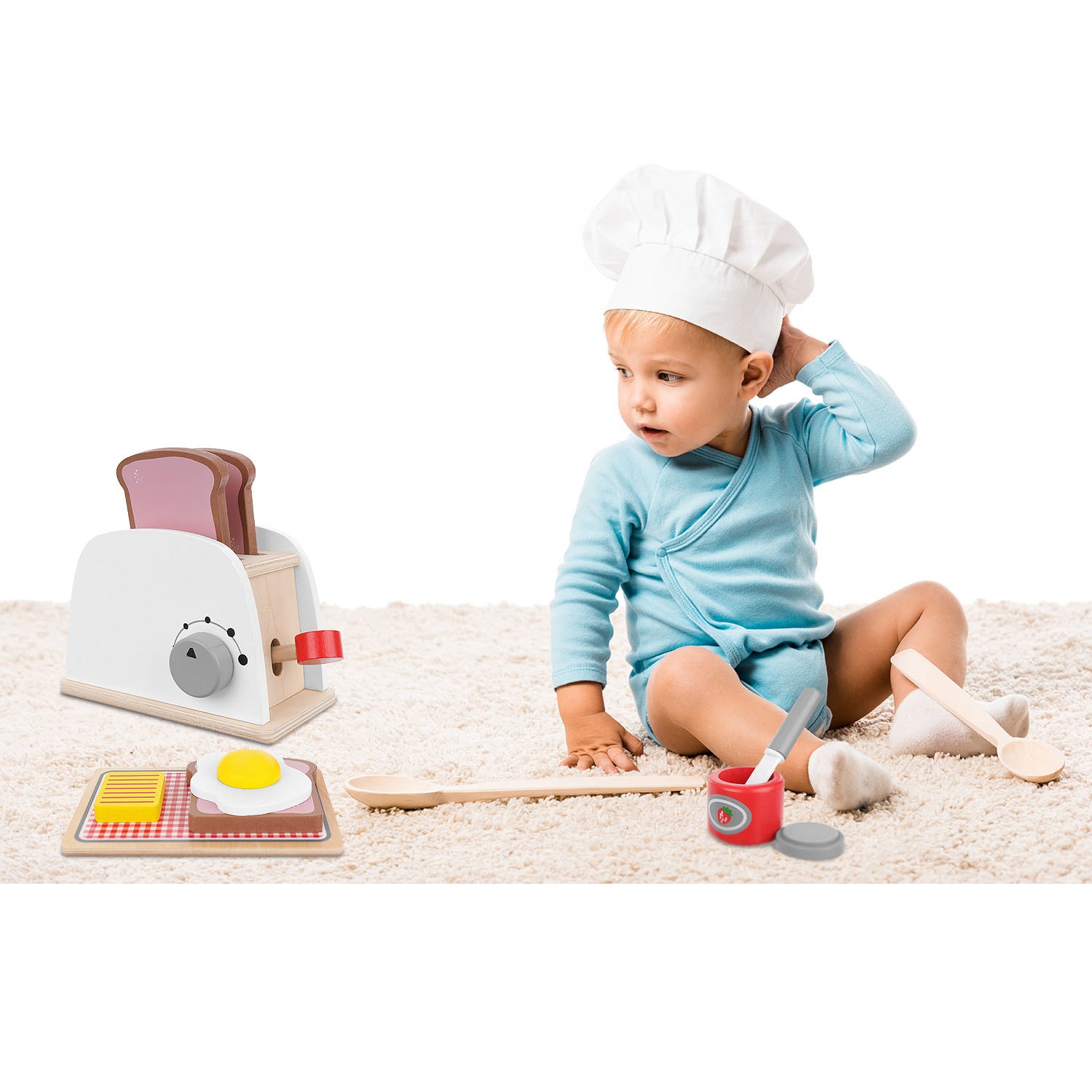 toddler boy in chefs hat sitting on carpet near two big wooden s