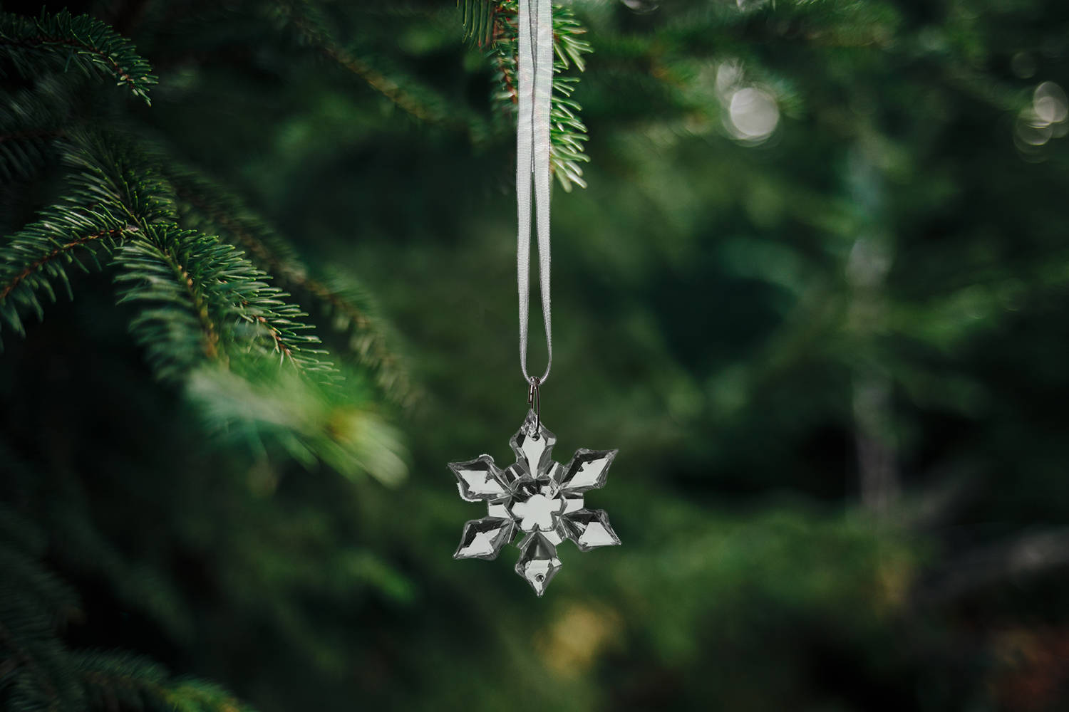 Closeup of a wooden snowflake-shaped Christmas ornament on a pine tree