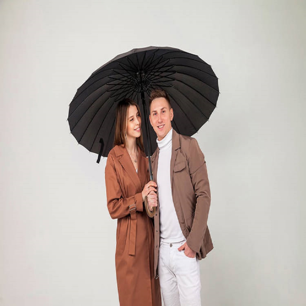 Young stylish couple with black umbrella shows love emotions